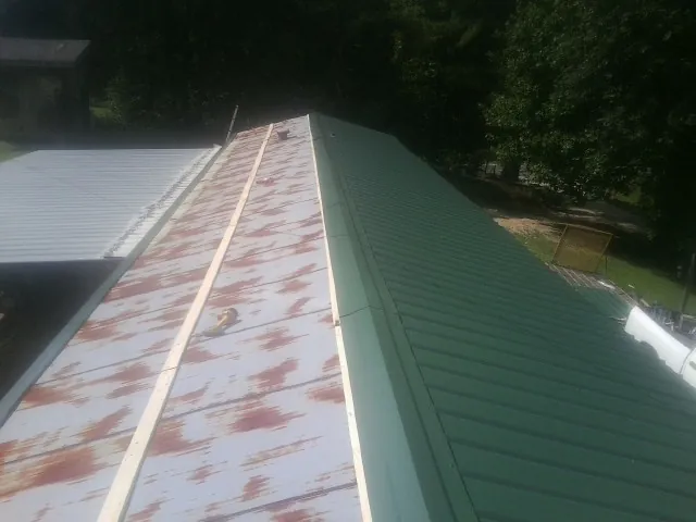 Old rusted panels beside newly installed green metal roofing — Wind Damage Roof Repair by Roofing Brothers in Maple Heights