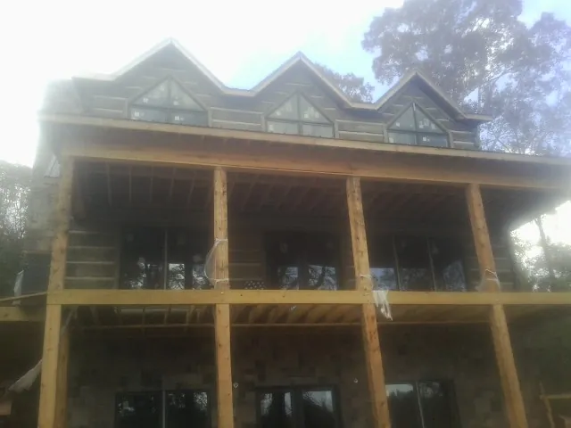 Dormers and porch framing on a large log home under construction — Roof Coating work by our crew in Maple Heights