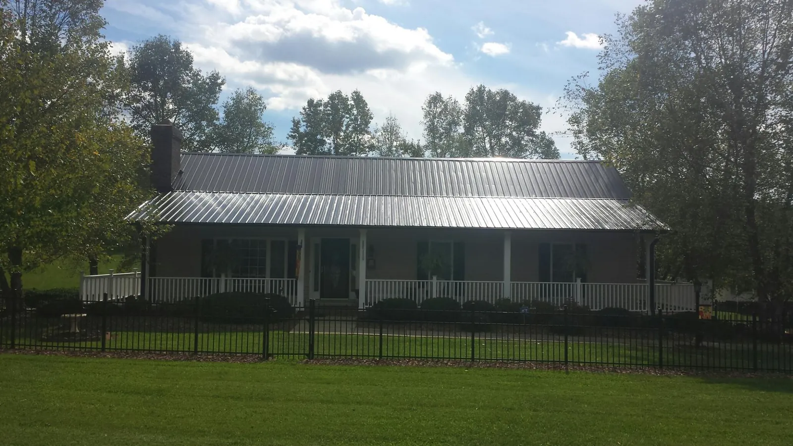 Gray metal roof on a brick ranch with a full width front porch — Gutter Guard Installation work by our crew in Maple Heights