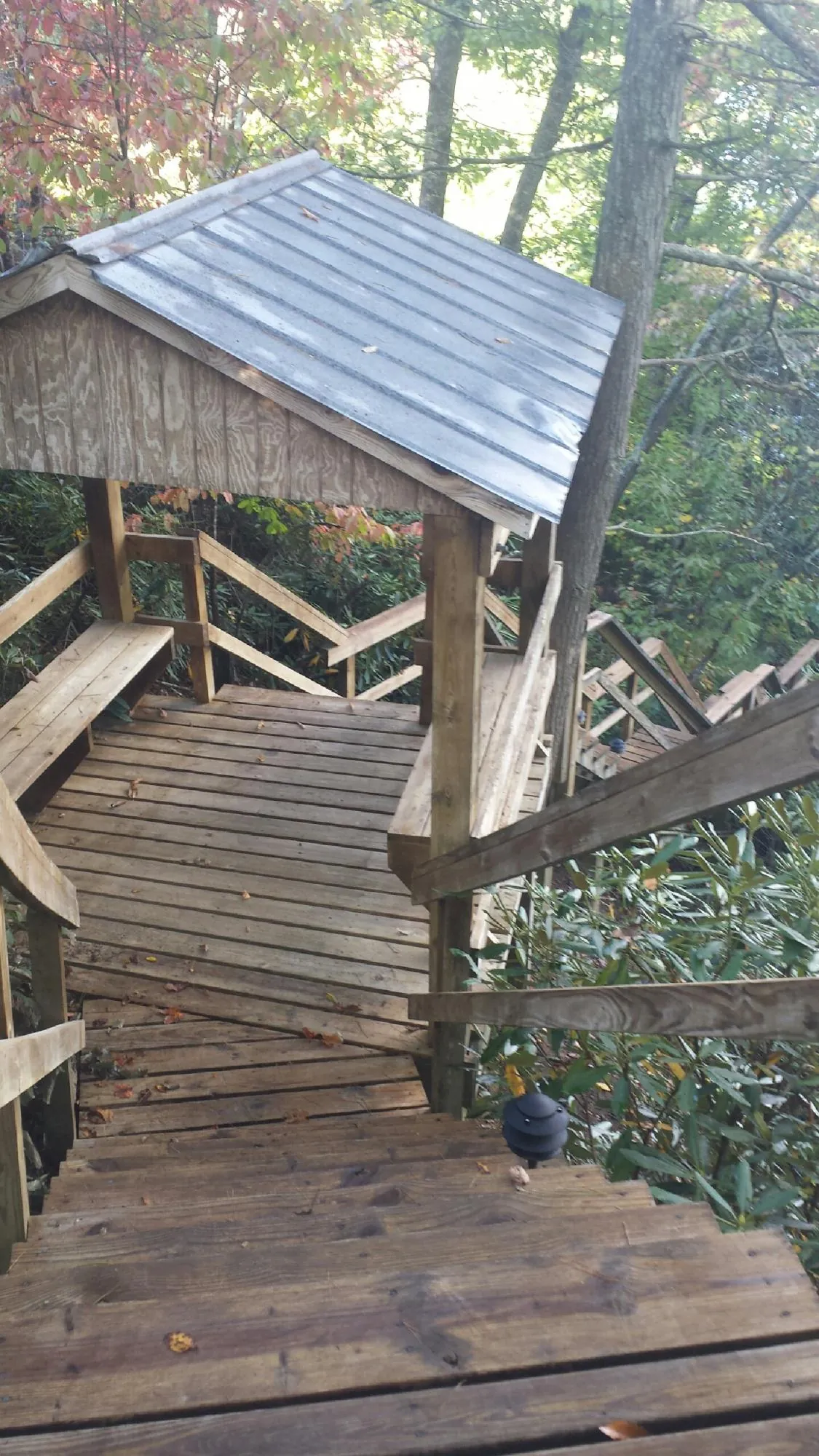 Metal roofed shelter over wooden steps on a wooded walkway — Skylight Repair & Installation work by our crew in Maple Heights