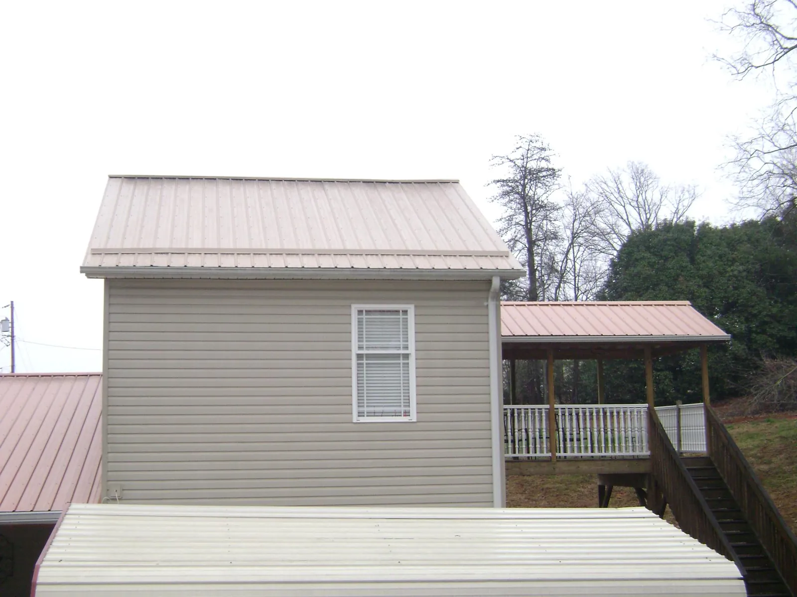 Tan metal roofs on a two story addition and attached porch, from a Roof Replacement job in Maple Heights