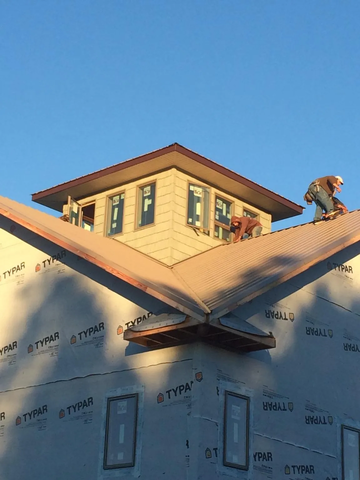 Roofers working around a rooftop cupola on a new metal roof at sunset — Roof Waterproofing in Maple Heights by Roofing Brothers